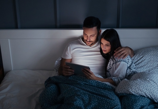 couple in bed watching sex with tablet